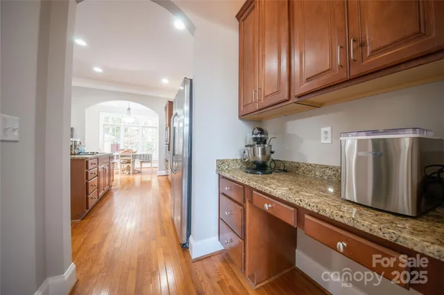 a kitchen with stainless steel appliances granite countertop a refrigerator a sink dishwasher a stove and white countertops with wooden floor