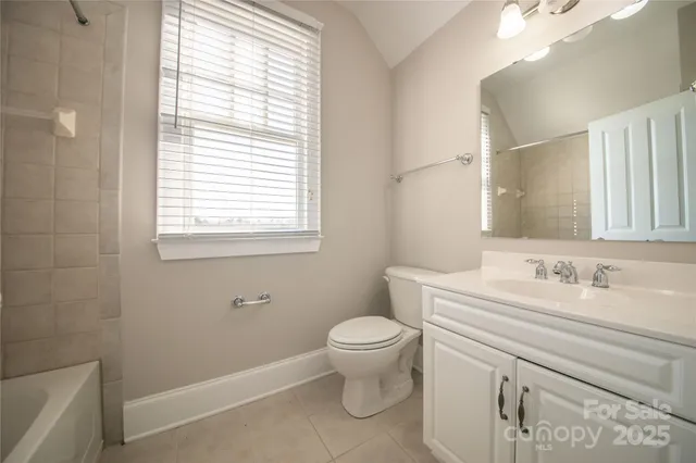 a bathroom with a granite countertop toilet a sink a mirror and a window