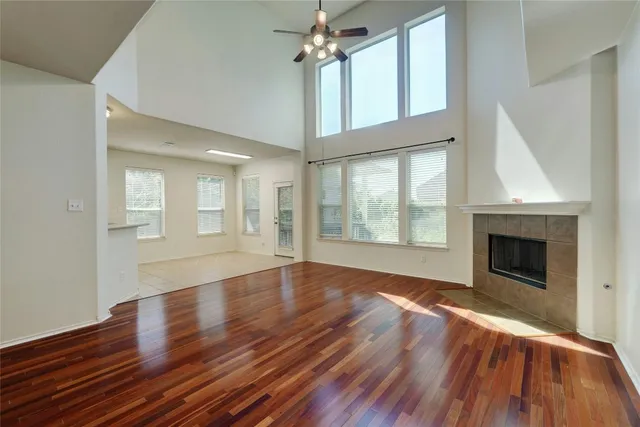 a view of an empty room with wooden floor fireplace and a window
