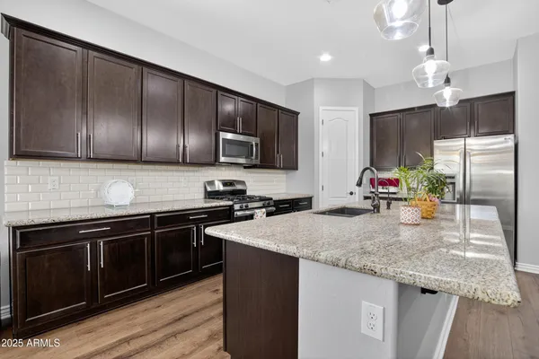 a kitchen with granite countertop stainless steel appliances a sink stove and refrigerator