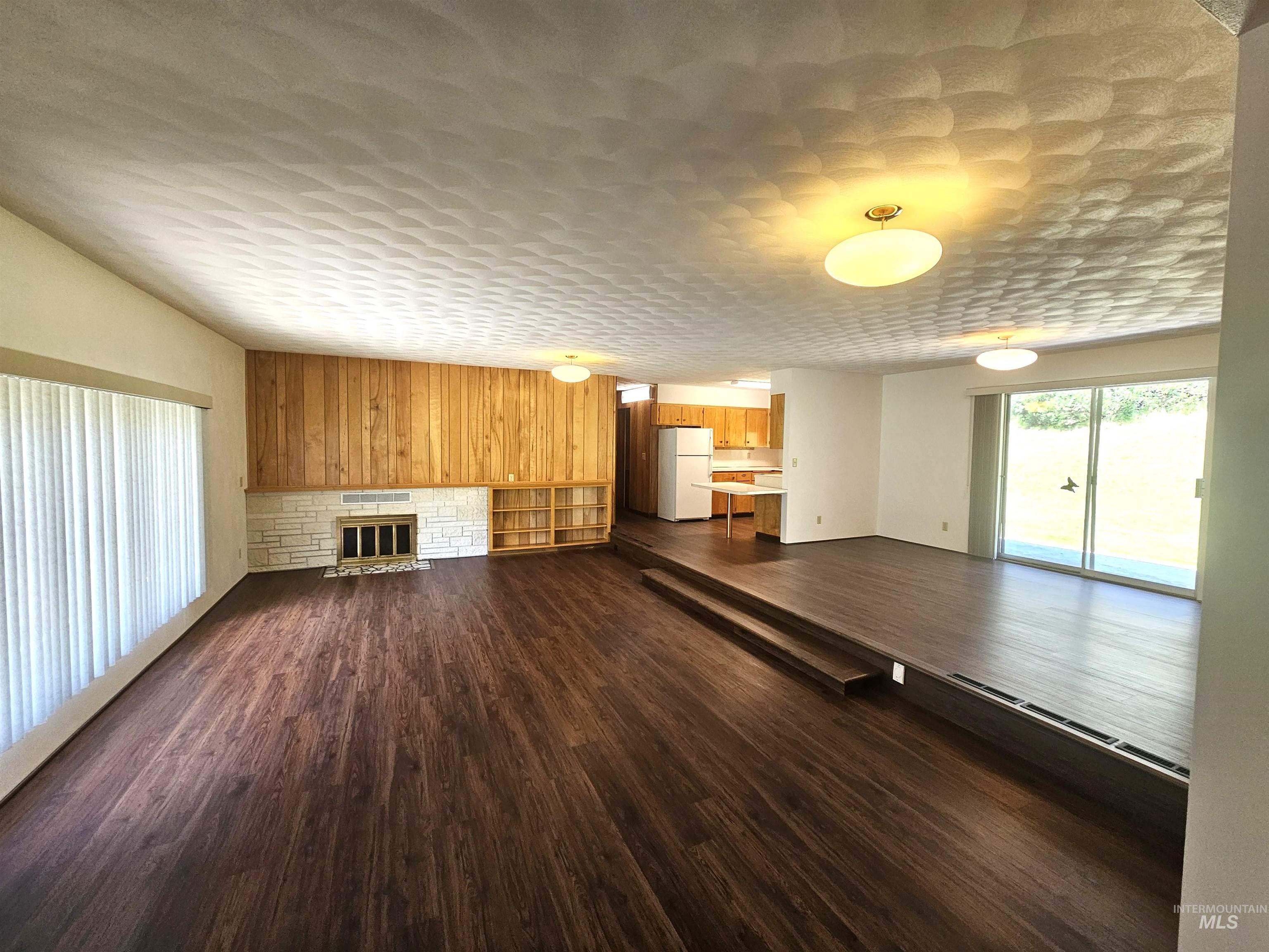 29865 Mission Creek Road Culdesac, ID 83524 - Photo 7 of 43 Spacious living area featuring wood-finish flooring and a stone fireplace with a wood panel accent wall
