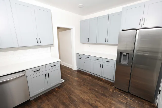 a kitchen with granite countertop white cabinets and refrigerator