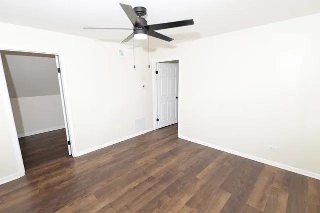 an empty room with wooden floor and a ceiling fan