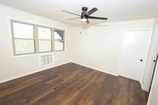 an empty room with wooden floor fan and windows