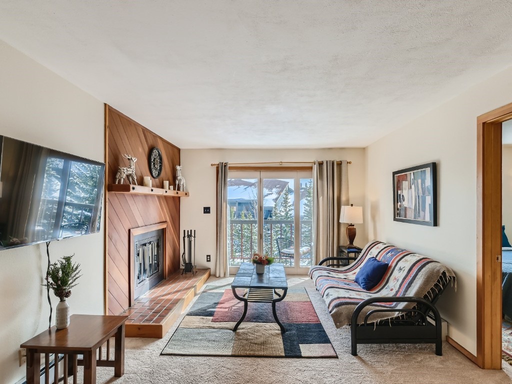 94300 Ryan Gulch Road, Unit 94402 Silverthorne, CO 80498 - Photo 4 of 27 a living room with furniture large window and a fireplace