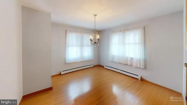 a bedroom with a bed and dresser with wooden floor