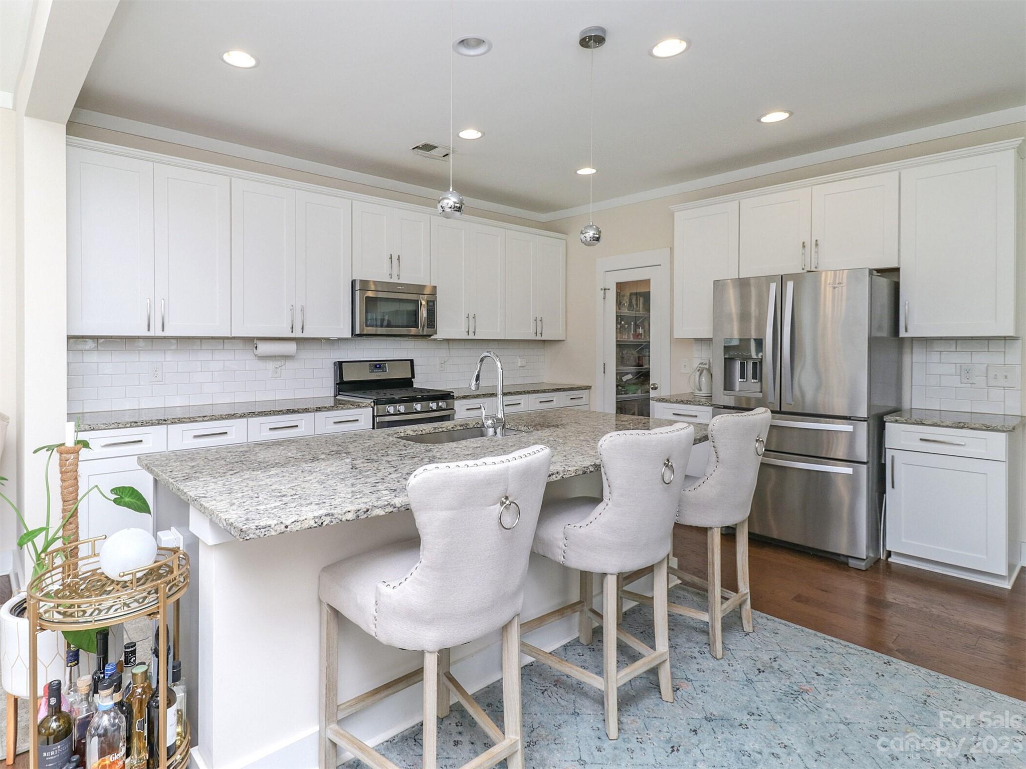 2634 Double Oaks Road Charlotte, NC 28206 - Photo 16 of 48 a kitchen with stainless steel appliances granite countertop a stove top oven a refrigerator a sink and a dining table with white cabinets