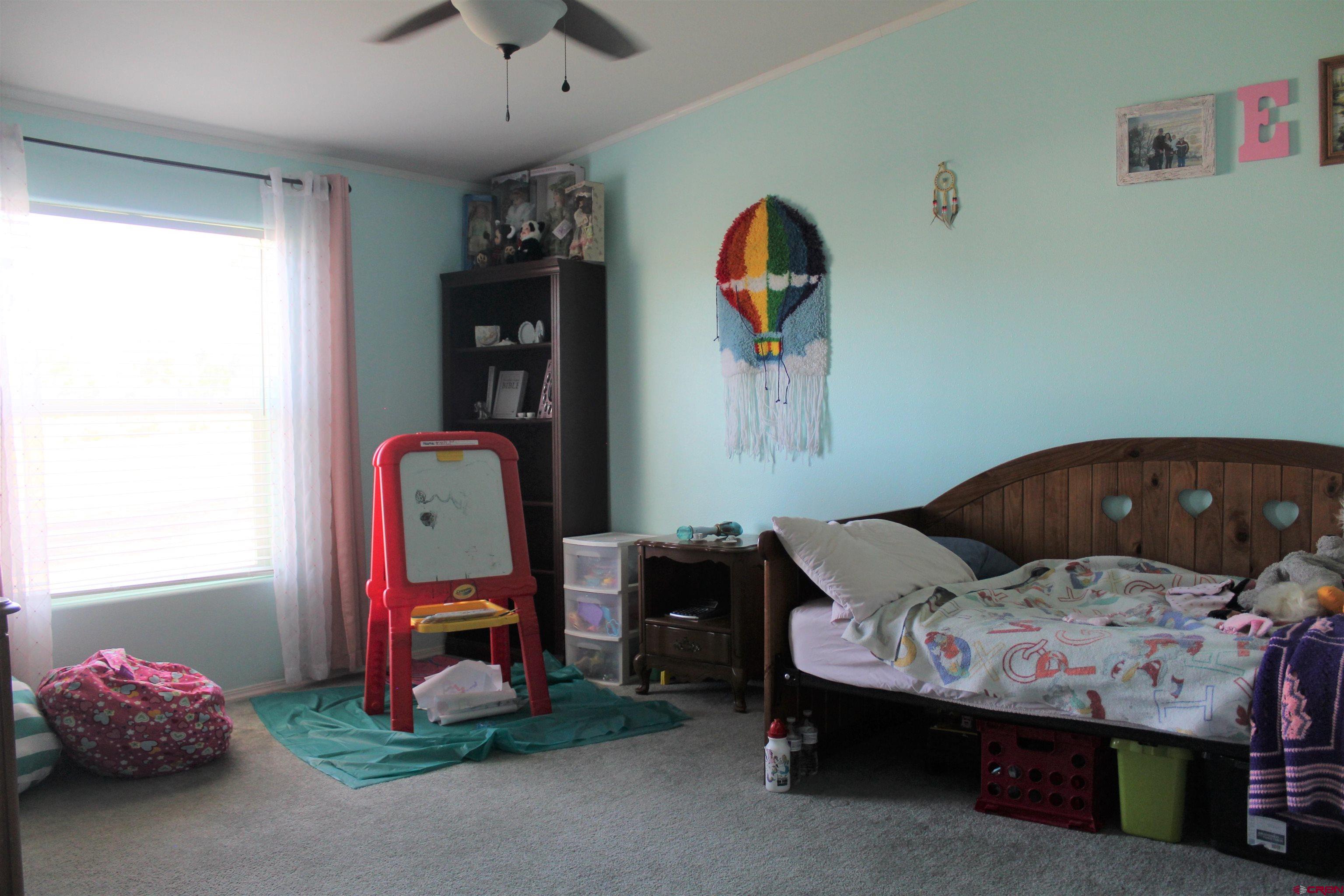 16875 Ember Road Cedaredge, CO 81413 - Photo 23 of 31 a bedroom with a bed and a chandelier