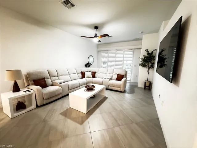 a living room with furniture a flat screen tv and a ceiling fan