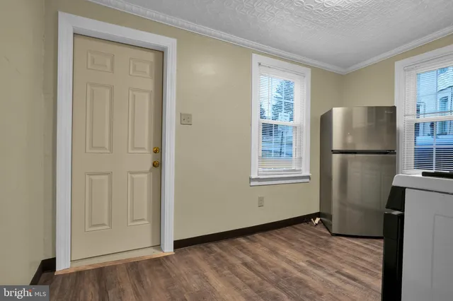 a view of a kitchen with wooden floor and refrigerator in kitchen