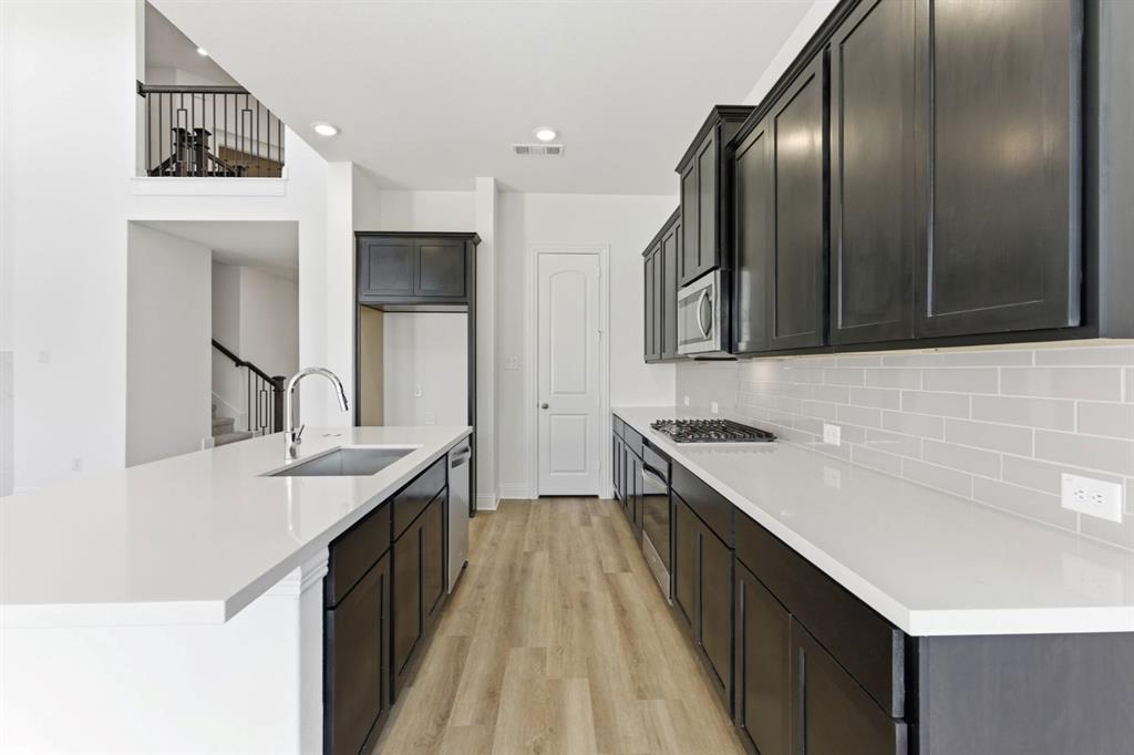 241 Bay Laurel Road McKinney, TX 75071 - Photo 12 of 32 a kitchen with stainless steel appliances granite countertop a sink stove and refrigerator