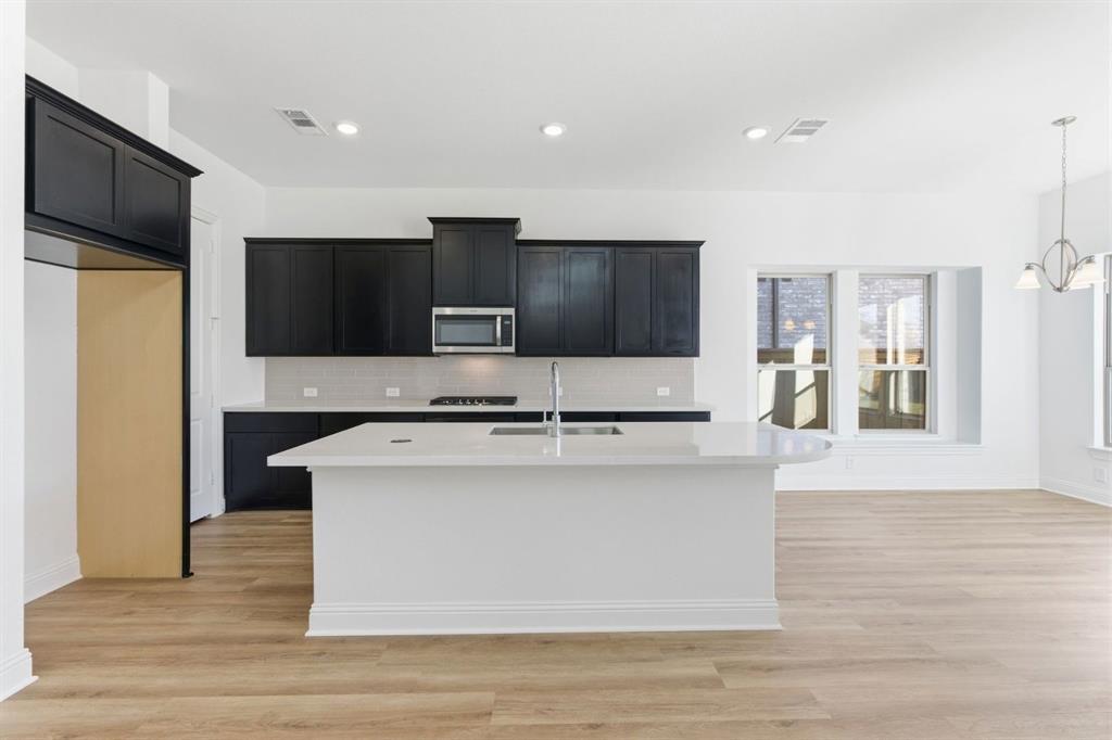241 Bay Laurel Road McKinney, TX 75071 - Photo 10 of 32 a large kitchen with stainless steel appliances a large counter top a stove and a refrigerator