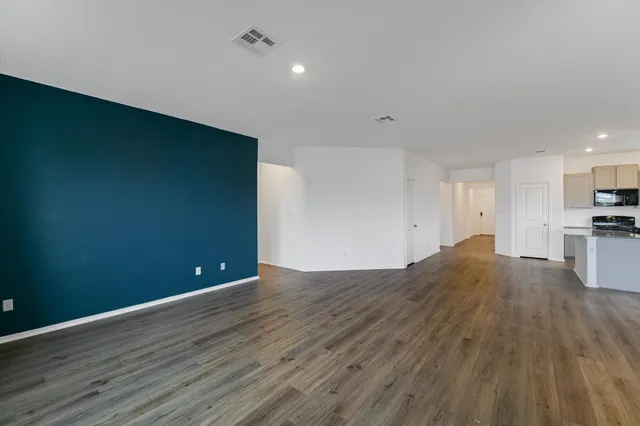 a view of kitchen and empty room with wooden floor