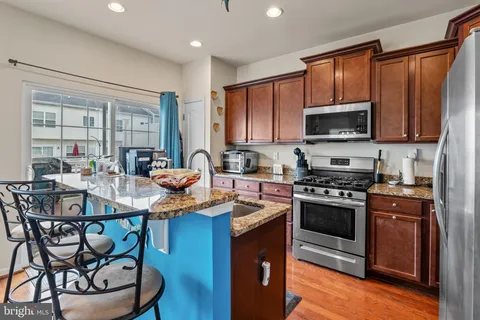 a kitchen with stainless steel appliances granite countertop a stove top oven a sink dishwasher a dining table and chairs