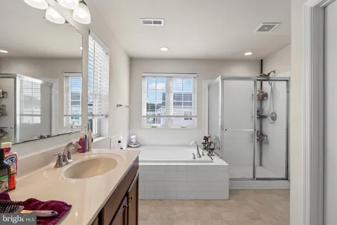 a bathroom with a tub sink double vanity mirror and shower