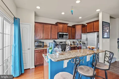 a kitchen with granite countertop kitchen island stainless steel appliances a sink a stove a refrigerator cabinets and dining table