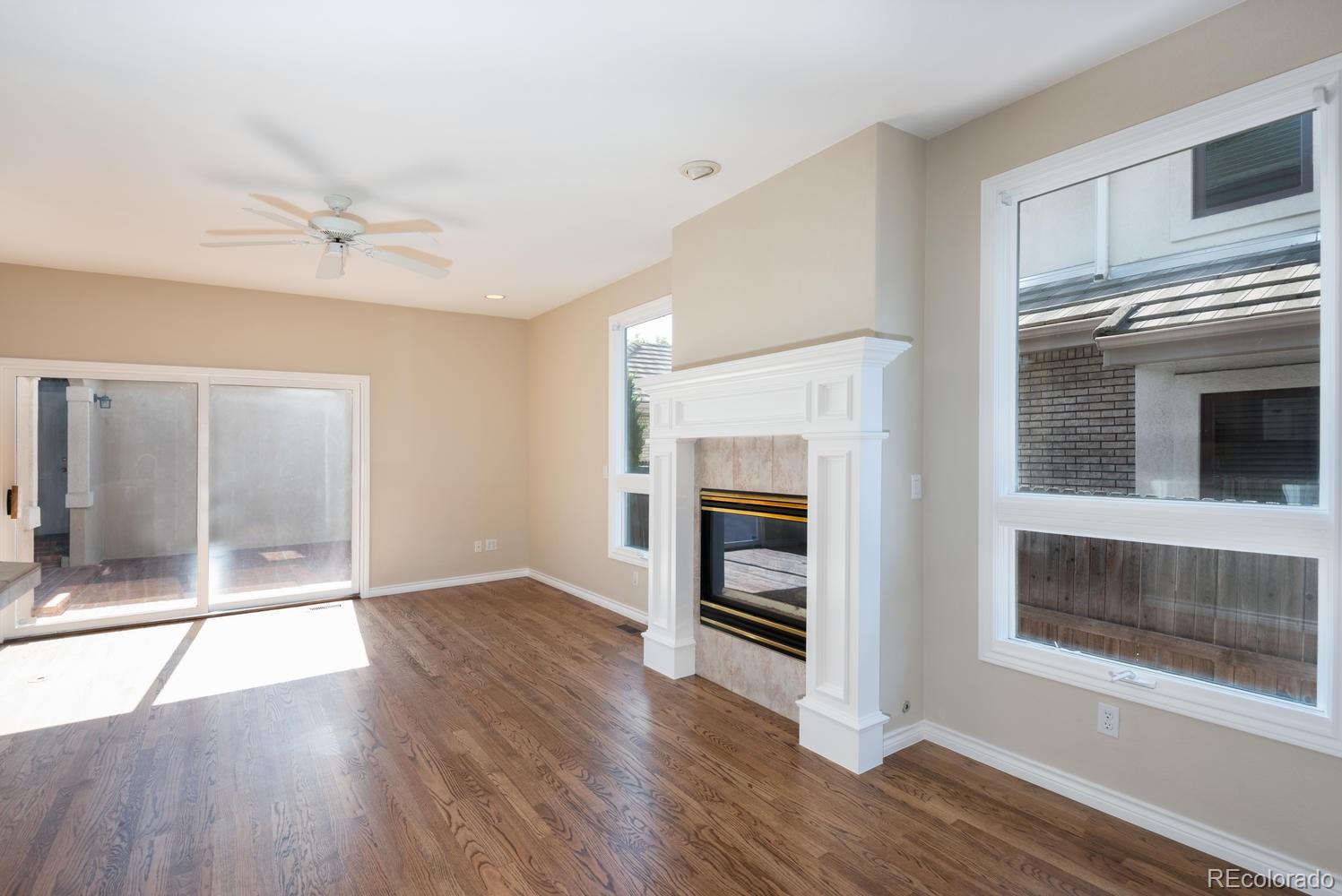 210 Cook Street Denver, CO 80206 - Photo 7 of 26 an empty room with wooden floor a ceiling fan and windows