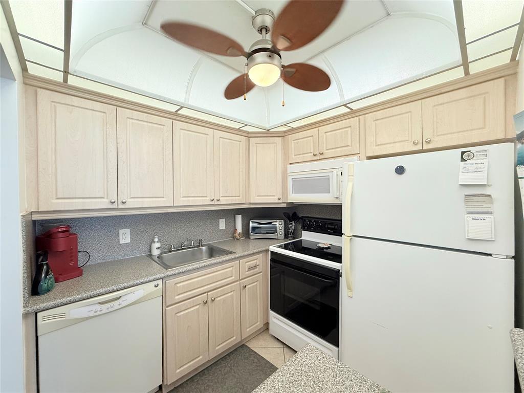 53 Markham C, Unit 53 Deerfield Beach, FL 33442 - Photo 8 of 30 a kitchen with stainless steel appliances granite countertop a refrigerator sink and cabinets