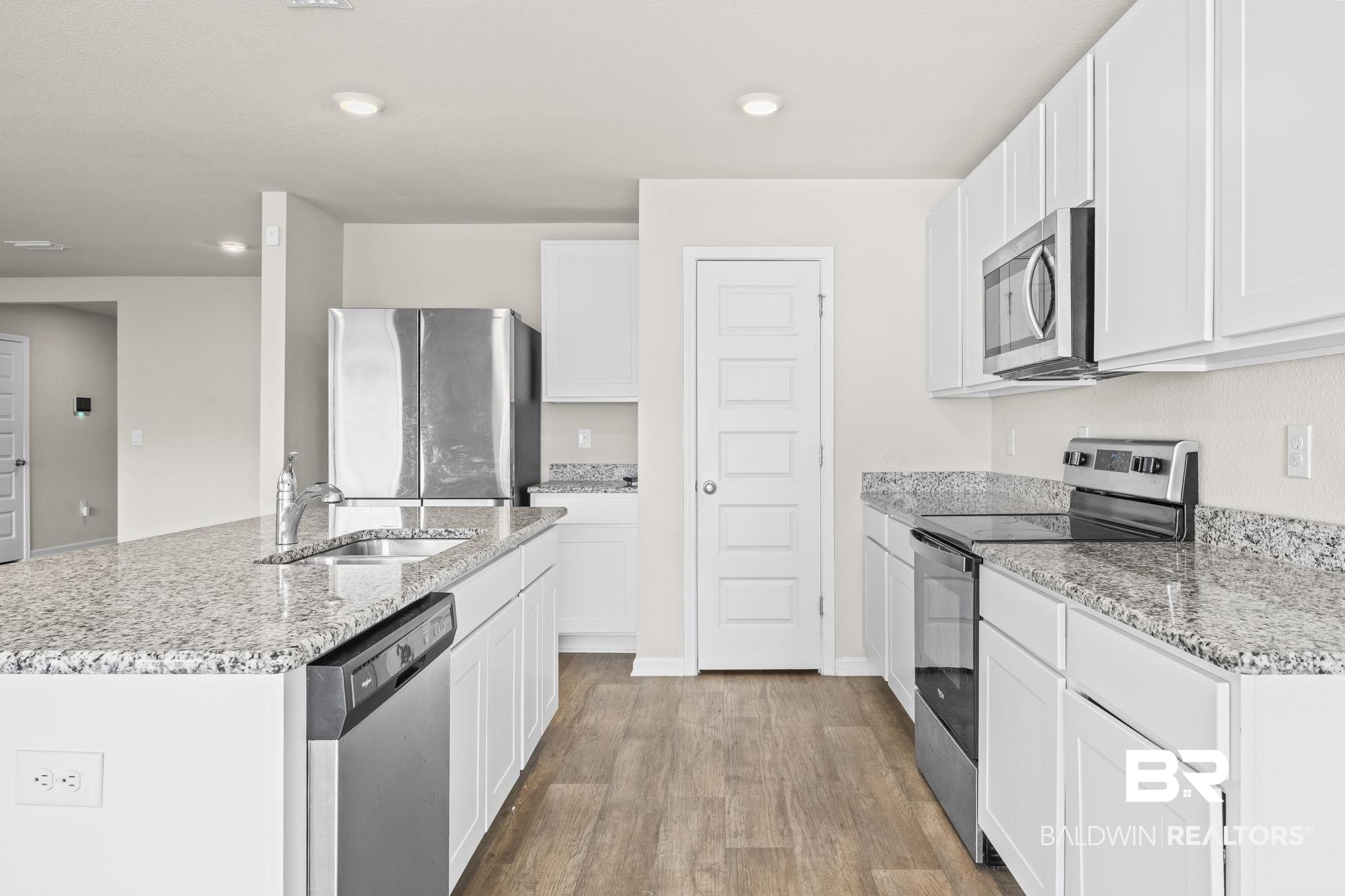 3090 Camino Real Loop Lillian, AL 36549 - Photo 15 of 29 Kitchen featuring stainless steel appliances, a center island with sink, light wood-style floors, light stone counters, and white cabinets