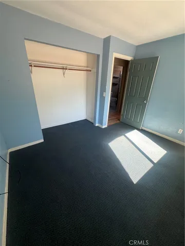 a view of an empty room with wooden floor and closet