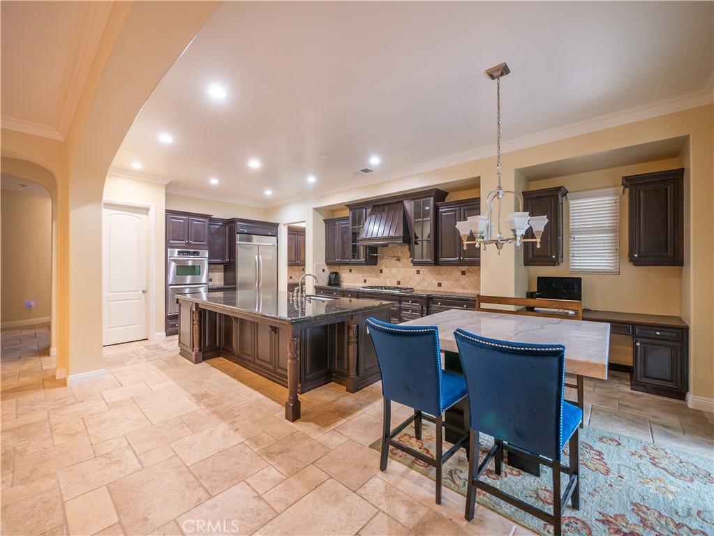 8111 Sunset Rose Drive Corona, CA 92883 - Photo 5 of 19 a kitchen with stainless steel appliances kitchen island granite countertop a table chairs and a refrigerator