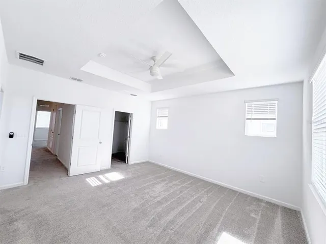 an empty room with a ceiling fan and windows