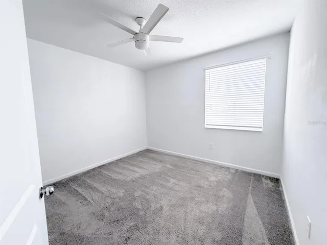 an empty room with a window and a fan