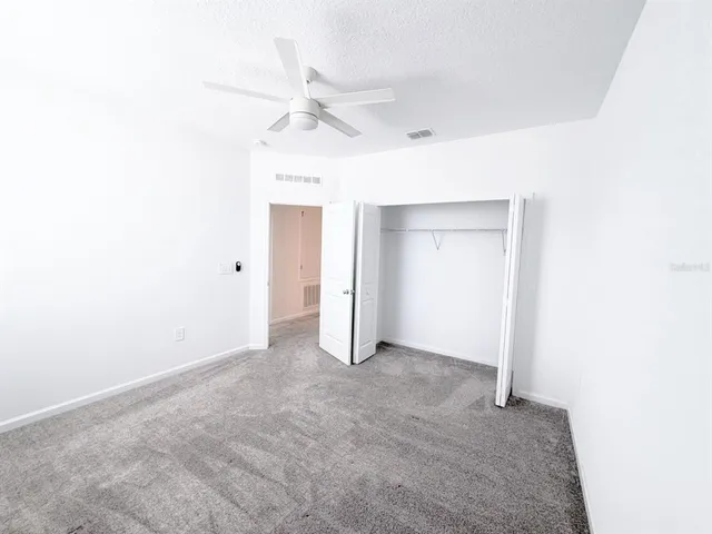 an empty room with a ceiling fan and closet