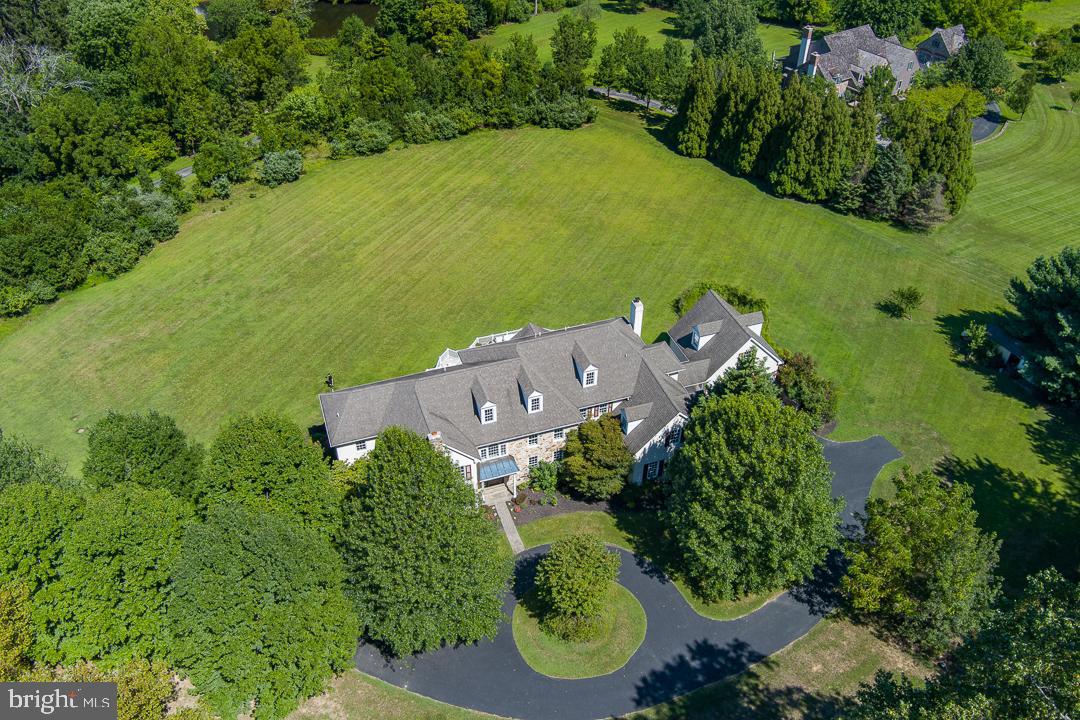 an aerial view of a residential houses with outdoor space and trees all around