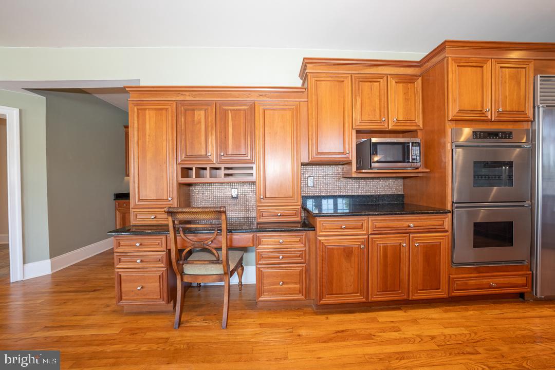 2 Spring Meadows Farm Lane Malvern, PA 19355 - Photo 13 of 63 a kitchen with stainless steel appliances granite countertop a stove top oven a refrigerator a dining table and chairs with wooden floor