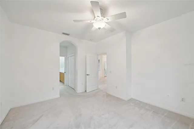 an empty room with a chandelier fan and closet area