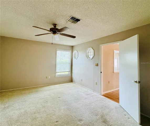 a view of a livingroom with a chandelier fan and windows