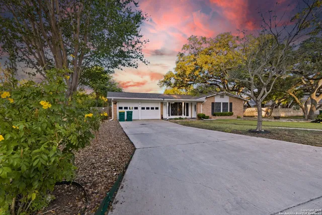 a front view of a house with a garden and trees