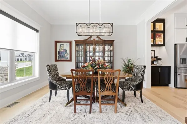 a view of a dining room and livingroom with furniture wooden floor a chandelier