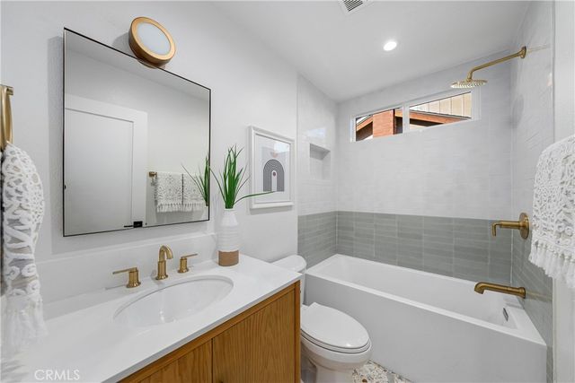 a bathroom with a granite countertop sink a toilet and shower