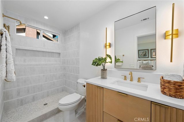 a bathroom with a granite countertop sink a toilet and shower