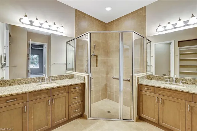 a bathroom with a granite countertop double vanity sink mirror and shower