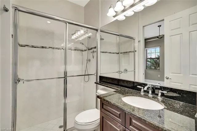 a bathroom with a granite countertop sink mirror vanity and toilet