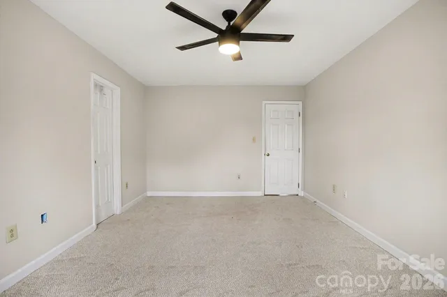 an empty room with a ceiling fan and window