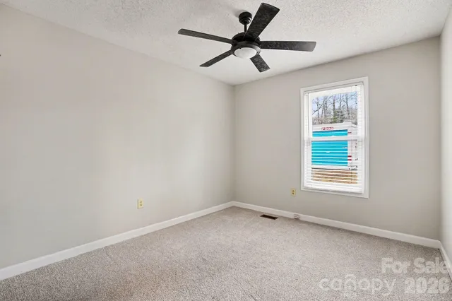 an empty room with a window and a fan