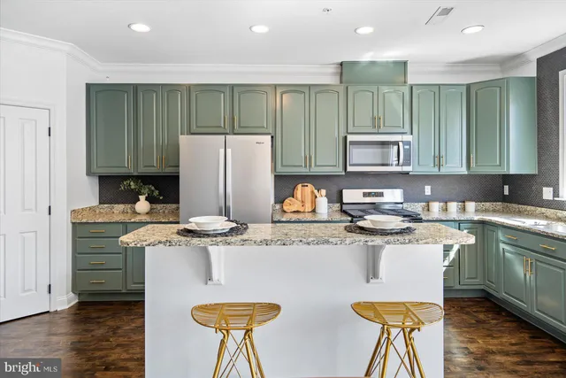 a kitchen with stainless steel appliances granite countertop a stove a refrigerator a sink a dining table and chairs