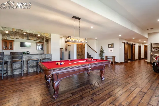 a room with pool table flat screen tv and wooden floor