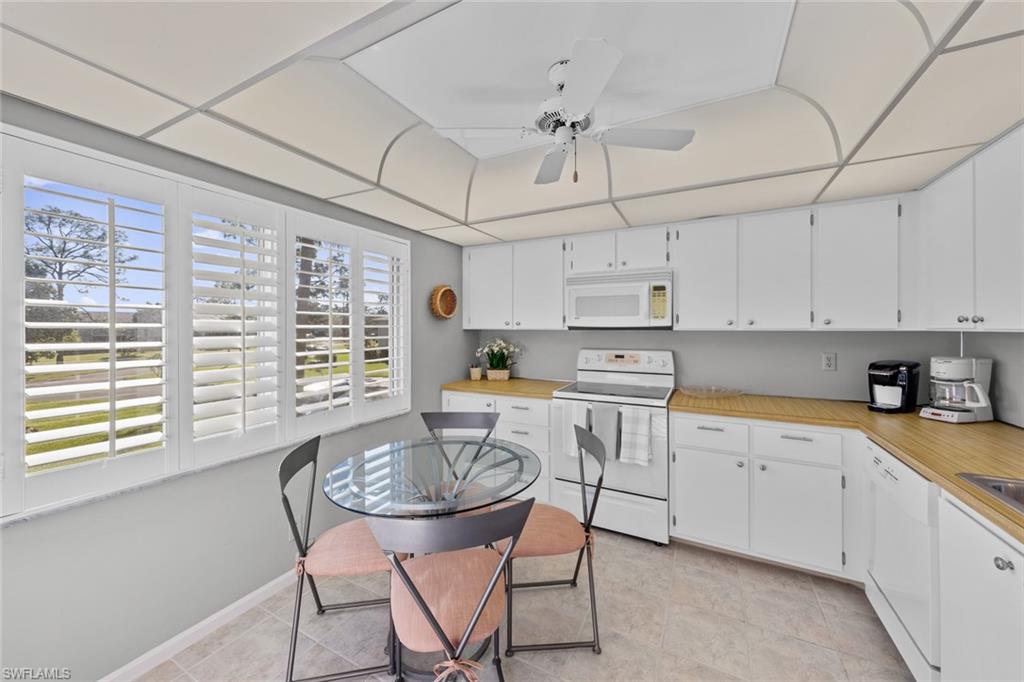 273 Albi Road, Unit 4 Naples, FL 34112 - Photo 16 of 50 Kitchen featuring a healthy amount of sunlight, light tile patterned flooring, white appliances, and white cabinetry