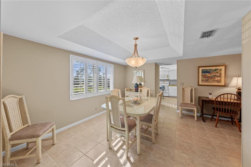 273 Albi Road, Unit 4 Naples, FL 34112 - Photo 8 of 50 Dining area featuring light tile patterned floors, a textured ceiling, and a tray ceiling