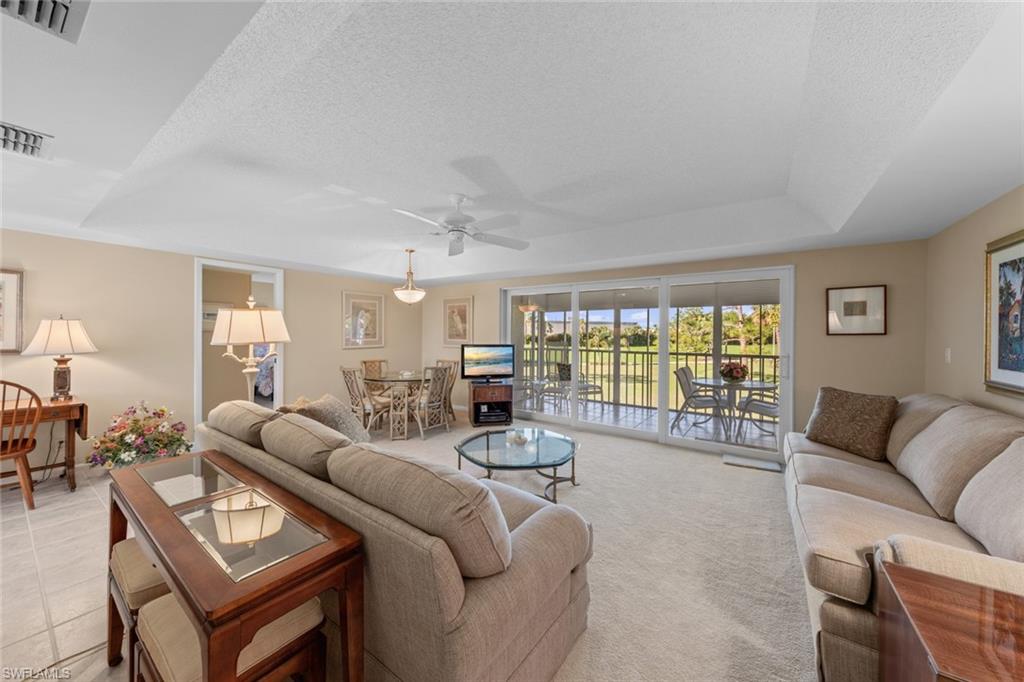 273 Albi Road, Unit 4 Naples, FL 34112 - Photo 9 of 50 Living room with a textured ceiling, light colored carpet, ceiling fan, and a tray ceiling
