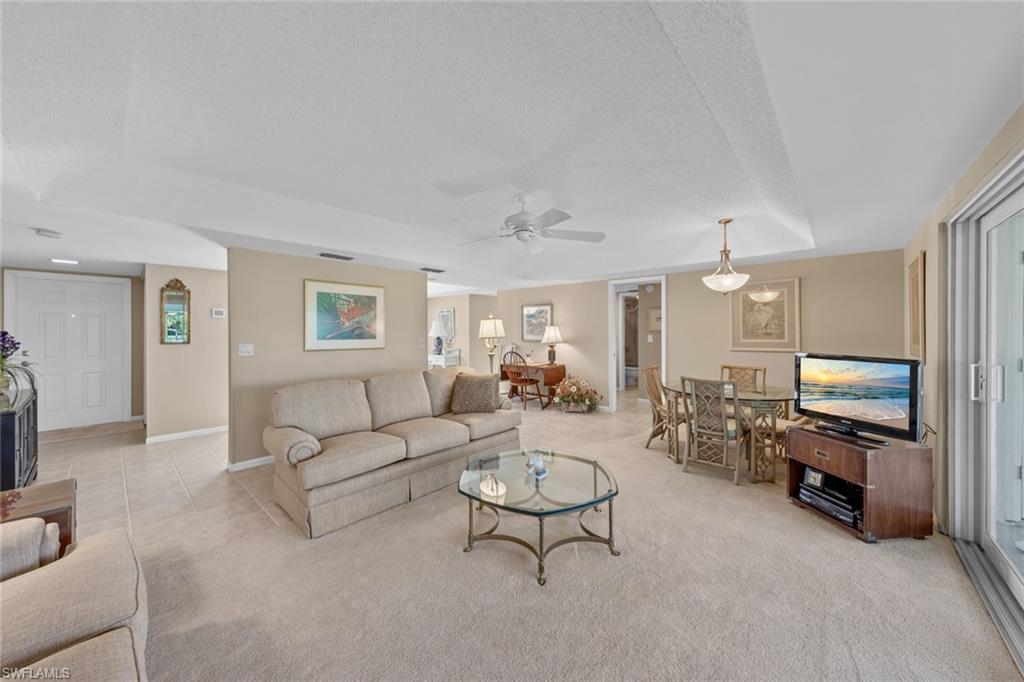 273 Albi Road, Unit 4 Naples, FL 34112 - Photo 10 of 50 Carpeted living room with a textured ceiling, a raised ceiling, and ceiling fan