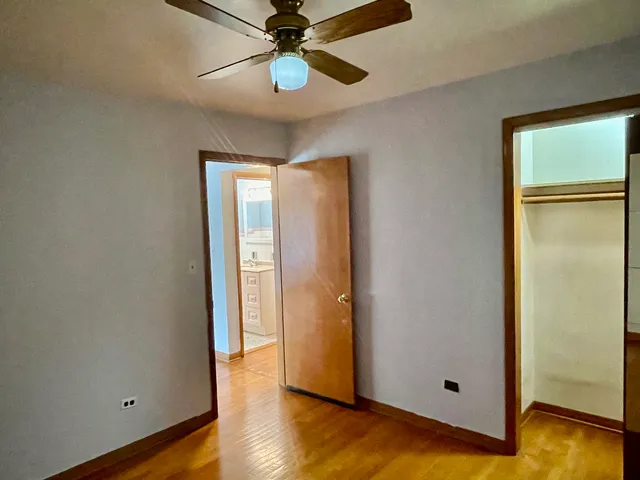 a view of a hallway with wooden floor and chandelier fan