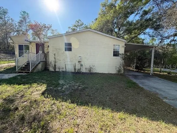 a view of a house with backyard and trees