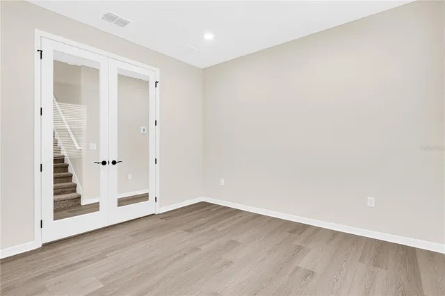 an empty room with wooden floor & windows