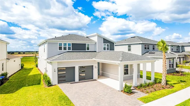 a view of a white house with a big yard and potted plants